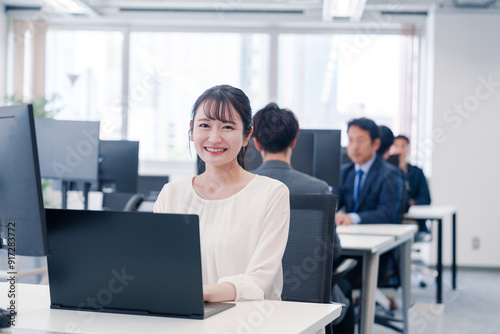 オフィスで笑顔でデスクワークをする若い女性