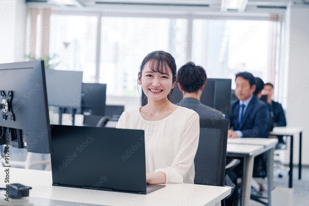 オフィスで笑顔でデスクワークをする若い女性