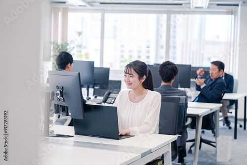 オフィスで笑顔でデスクワークをする若い女性