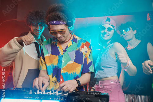 Εκτύπωση καμβά Young male deejay in headphones and stylish apparel bending over soundboard whil