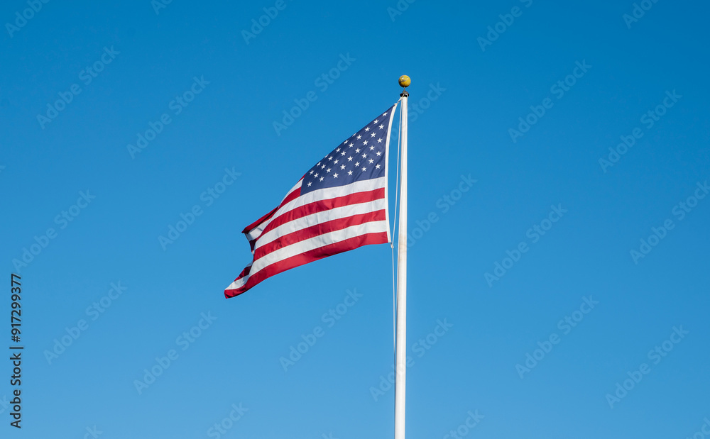 Isolated American Flag with clear blue sky in background Isolated American Flag with clear blue sky in background