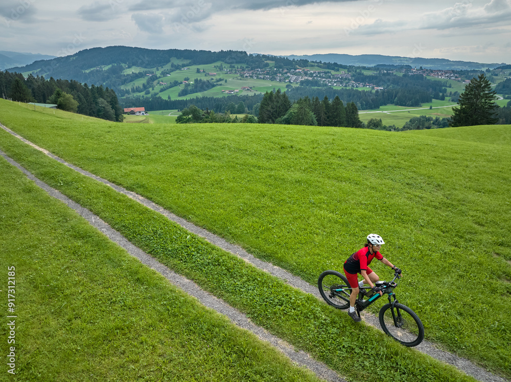 Obraz premium pretty senior woman riding her electric mountain bike in the Allgaeu mountains near Oberstaufen and Stiefenhofen, Bavaria, Germany