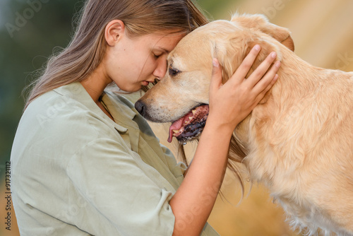 beautiful girl with golden retriever dog in wheat field at sunset