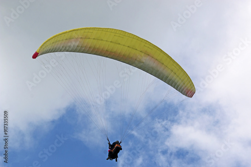 Tandem Paraglider flying in a cloudy sky 