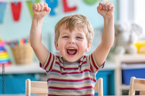 Happy child boy raising hands celebrating success in kindergarten