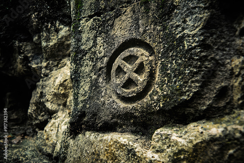 Ancient cryptic symbol etched into a weathered stone wall, hinting at forgotten mysteries and lost knowledge from a bygone era. photo