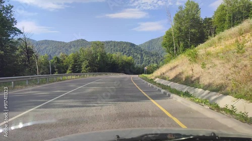 View from the car on the road passing through the forest on a winding mountain road.