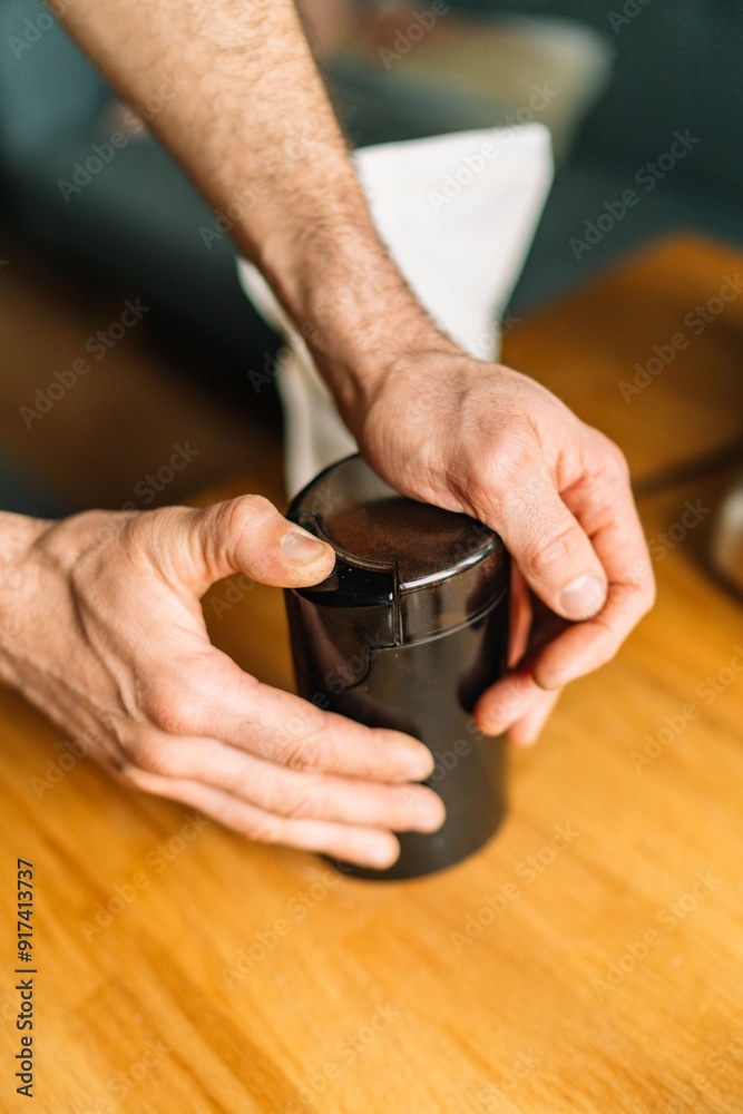 Close-up of male hands using an electric coffee grinder on a wooden table Close-up of male hands using an electric coffee grinder on a wooden table