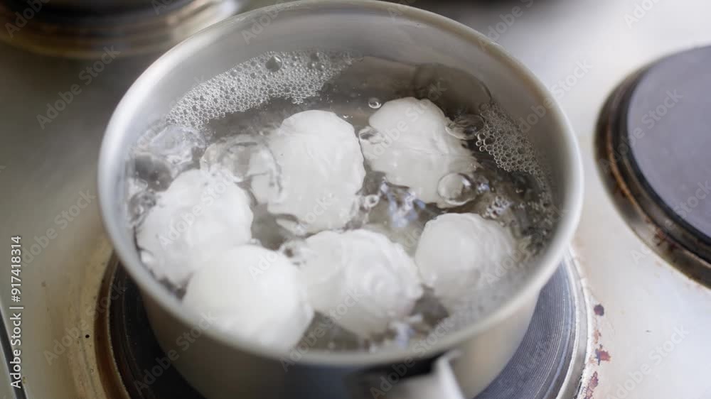 A pot containing eggs is boiling in water on the stove, clearly showcasing the process of cooking preparation. Slow motion A pot containing eggs is boiling in water on the stove, clearly showcasing the process of cooking preparation. Slow motion