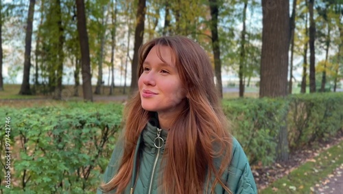 Beautiful young woman walking in the park in autumn. Enjoying the weather, smiling, breathing fresh air