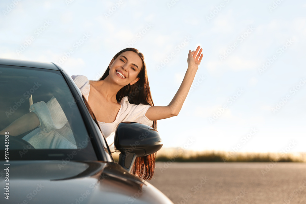 Smiling young woman leaning out of car window outdoors. Enjoying trip Smiling young woman leaning out of car window outdoors. Enjoying trip