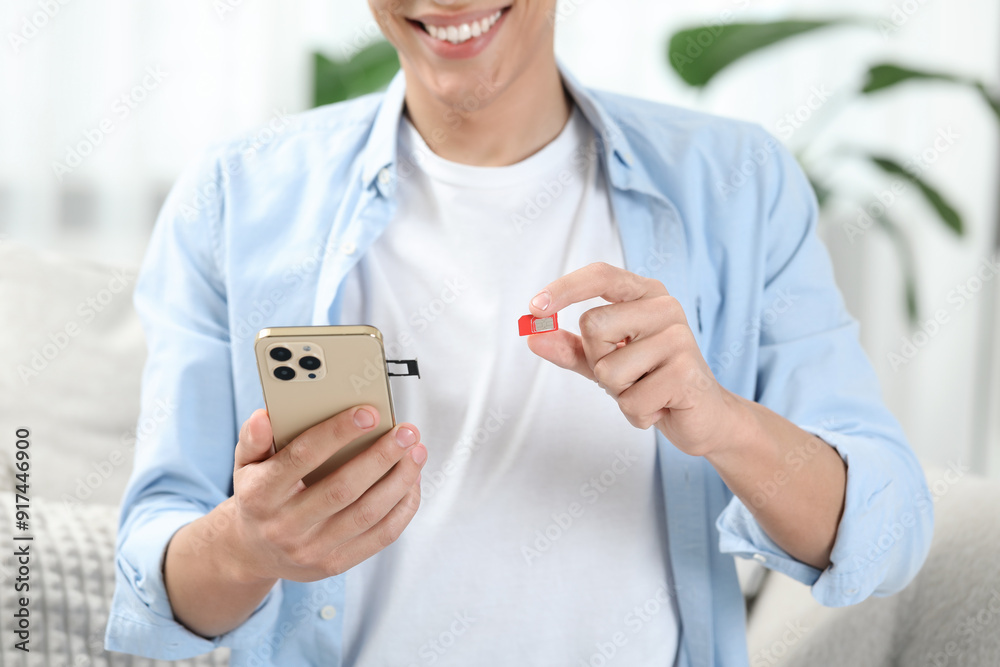 Man with SIM card and smartphone indoors, closeup Man with SIM card and smartphone indoors, closeup