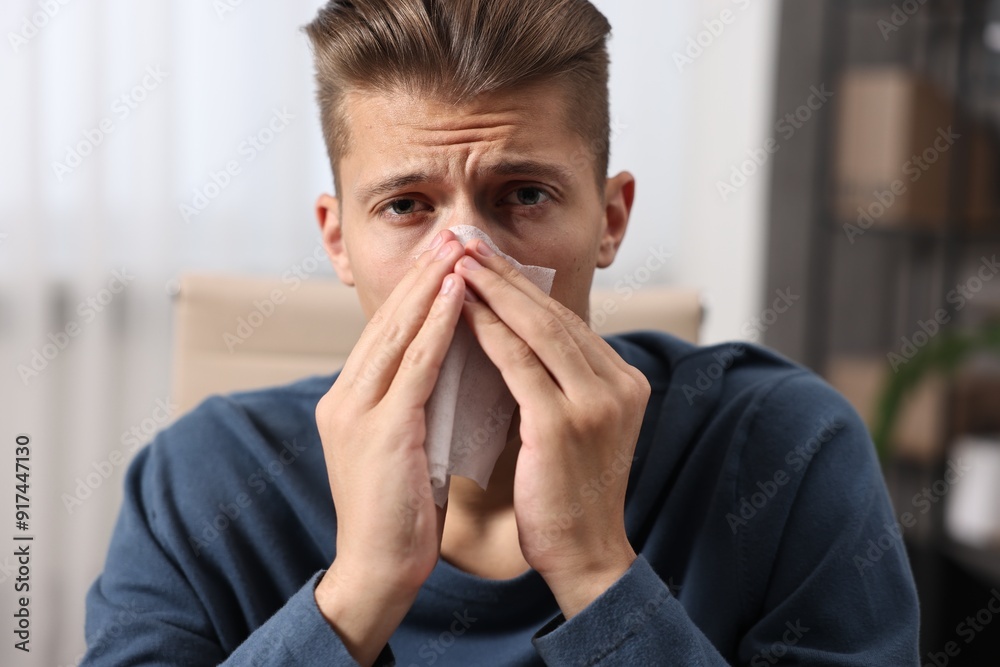 Young man with tissue suffering from sinusitis indoors Young man with tissue suffering from sinusitis indoors