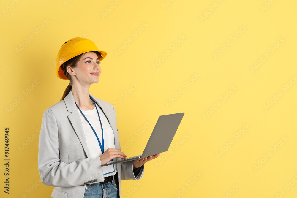 Engineer in hard hat with laptop on yellow background, space for text Engineer in hard hat with laptop on yellow background, space for text