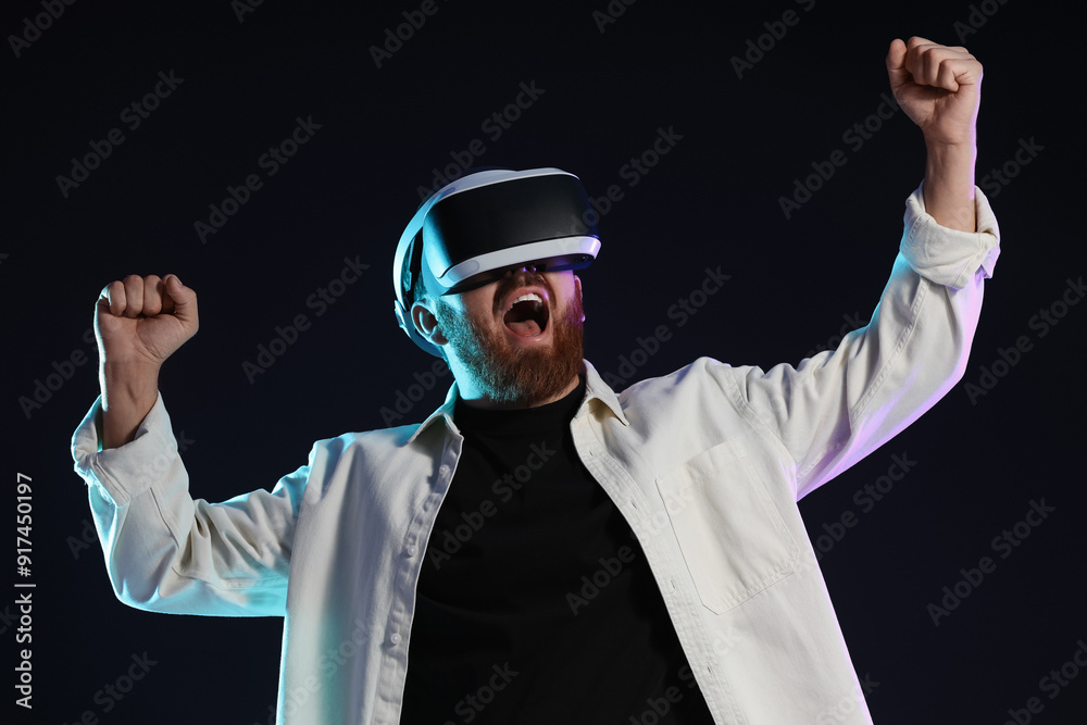 Emotional man using virtual reality headset on dark background in neon lights Emotional man using virtual reality headset on dark background in neon lights