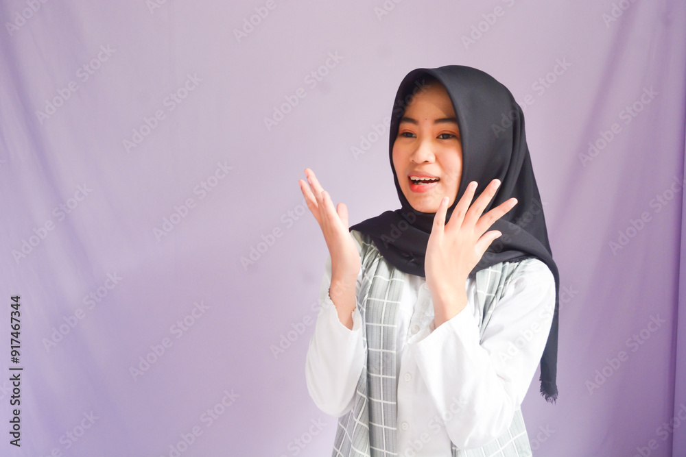 Portrait of smiling beautiful Asian woman in casual shirt and hijab holding a laptop and looking at camera isolated over white background. People religious lifestyle concept Portrait of smiling beautiful Asian woman in casual shirt and hijab holding a laptop and looking at camera isolated over white background. People religious lifestyle concept
