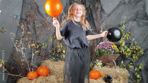 a girl with black and orange balloons dances and rejoices at the Halloween holiday. photo