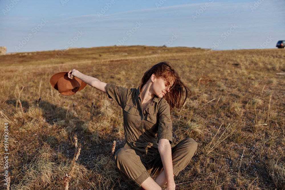 Woman sitting in the middle of a field with a hat on her head outdoor fashion portrait in nature beauty concept Woman sitting in the middle of a field with a hat on her head outdoor fashion portrait in nature beauty concept