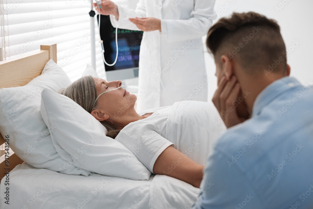 Coma patient. Sad young man near his unconscious mother in hospital Coma patient. Sad young man near his unconscious mother in hospital