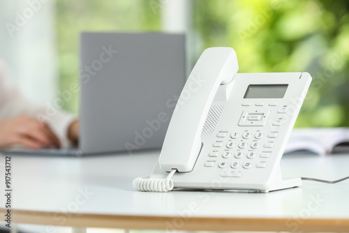 White telephone on table against blurred background, selective focus