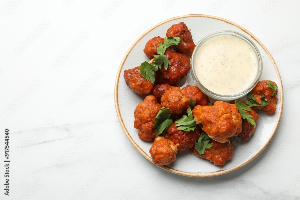 Baked cauliflower buffalo wings with parsley and sauce on white marble table, top view. Space for text Baked cauliflower buffalo wings with parsley and sauce on white marble table, top view. Space for text