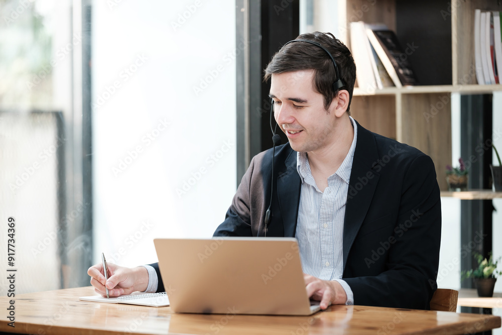 A man is sitting at a desk with a laptop and a pen A man is sitting at a desk with a laptop and a pen