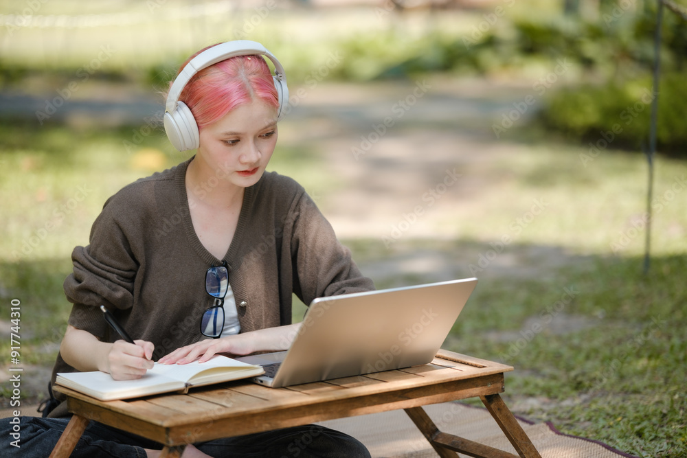 Young woman with a laptop and notes studying in the park for education in nature to relax and learn online. Young woman with a laptop and notes studying in the park for education in nature to relax and learn online.