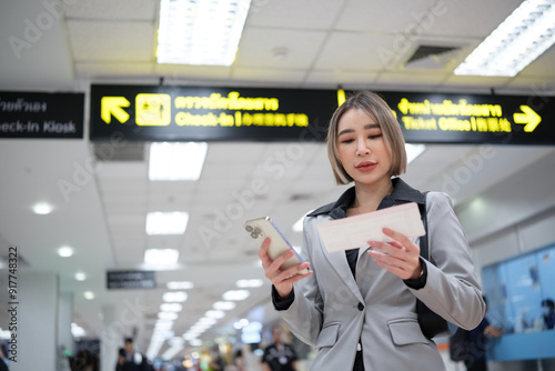 A woman is looking at her phone while reading a ticket