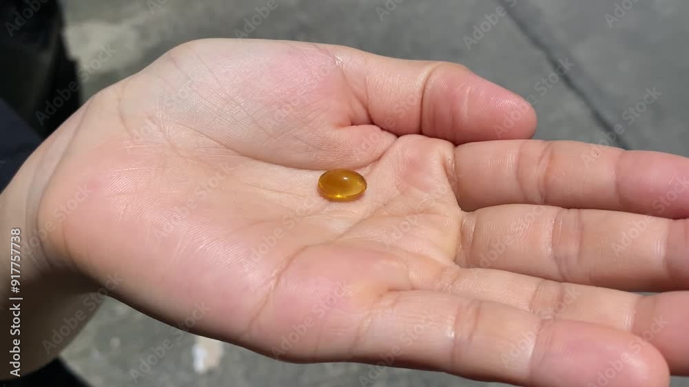 Vitamin D pill falling on woman hand outdoor sunny sunlight shine on capsule gel. Healthy lifestyle and dietary supplements concept. Vitamin D pill falling on woman hand outdoor sunny sunlight shine on capsule gel. Healthy lifestyle and dietary supplements concept.