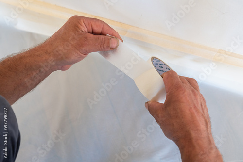 Gros plan illustrant la pose de bande cache pour une préparation avant peinture d'un bâtiment.  photo