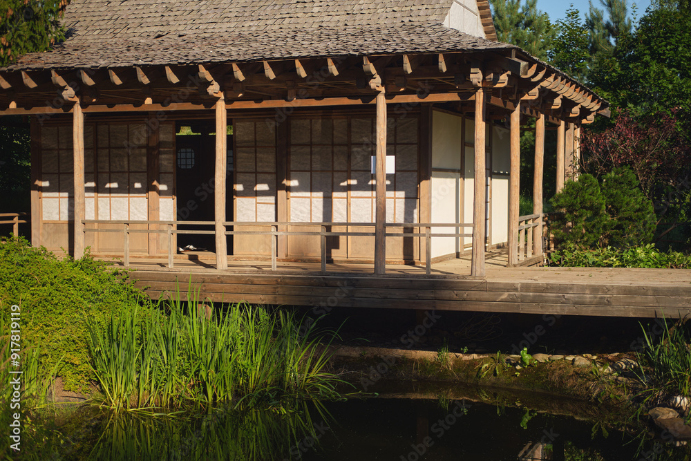 Traditional Japanese tea house with wooden structure and paper screens surrounded by lush greenery and pond. Cultural architecture and nature concept for design and print. Traditional Japanese tea house with wooden structure and paper screens surrounded by lush greenery and pond. Cultural architecture and nature concept for design and print.