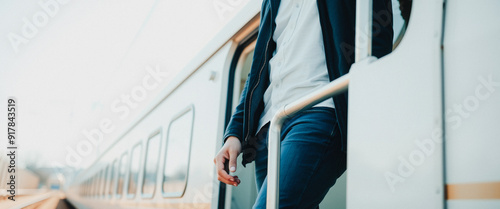 Man in Blue Jeans and a Jacket Stands By a Train Door