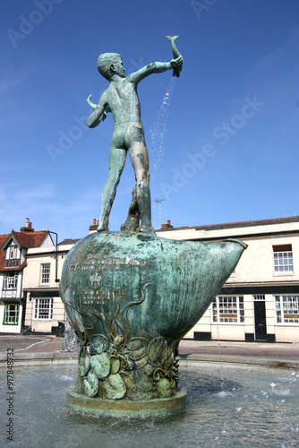 Bronze statue of a young boy holding fish with sea lions around the base of the fountain, St Michaels Fountain Square, Braintree, Essex, England photo