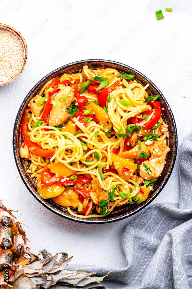 Egg noodles with stir fried chicken, pineapple, paprika, green onion, ginger, garlic, soy sauce and sesame seeds. White background, top view