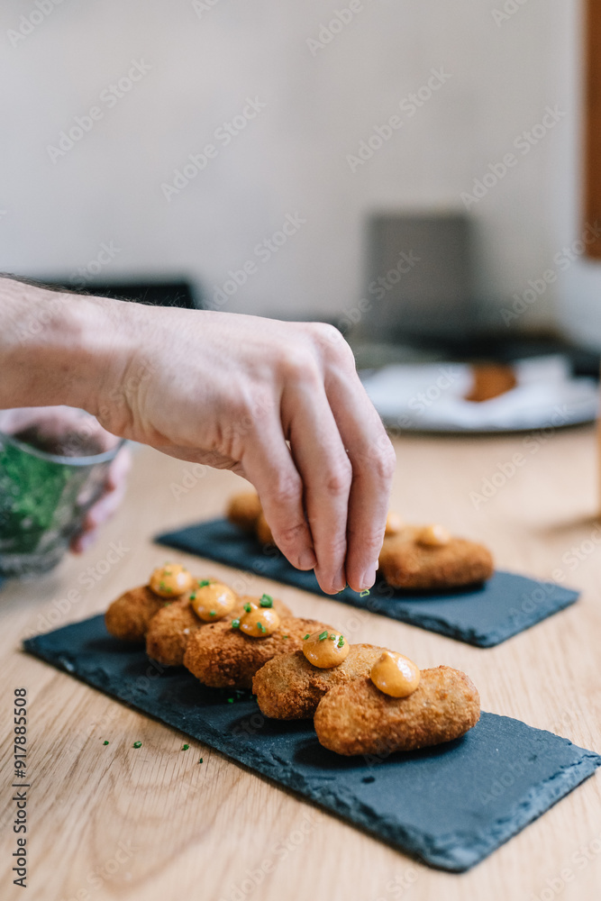 Cropped unrecognizable person garnishing food on slate Cropped unrecognizable person garnishing food on slate