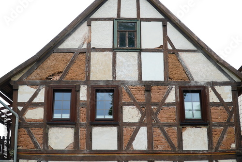 Street view of an old, typical half timbered gable, with the facade compartments classically filled in with loam, straw and bricks. Partial facade of an abandoned house in Elende, Thuringia, Germany. photo