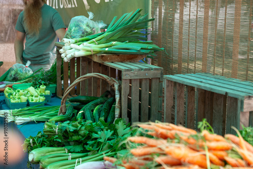 Freshly harvested organic carrots, shallots, zucchini, green onions, peppers and leeks with backdrop of sustainable wood crate and shades at Trout Lake Farmer's Market in British Columbia 