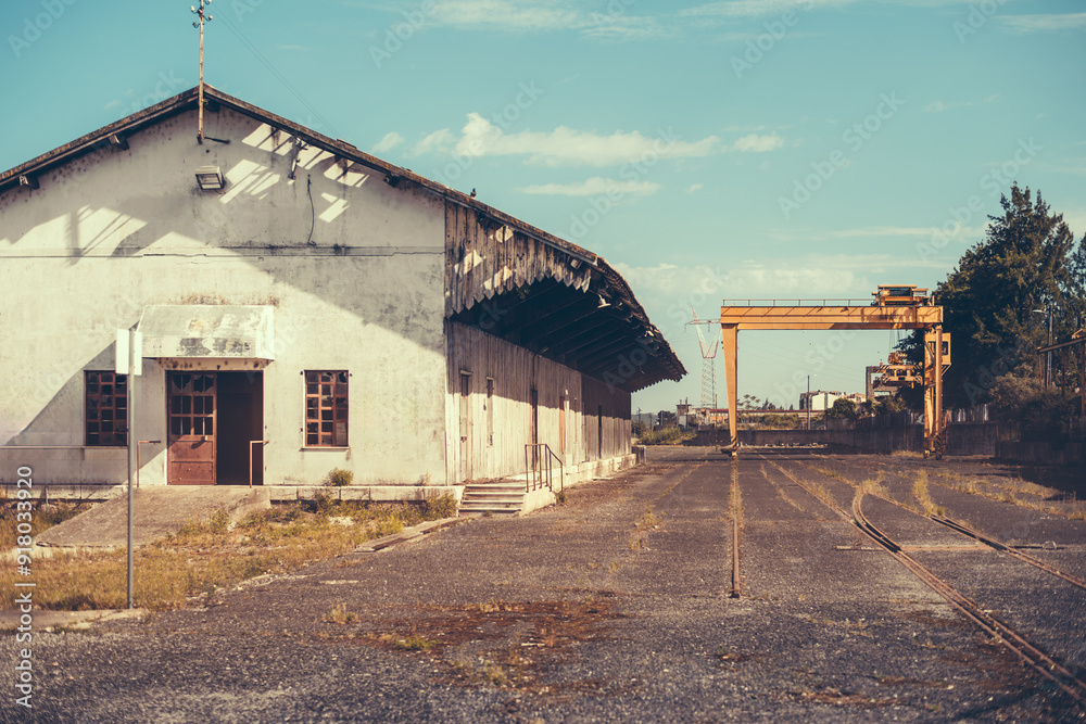 Abandoned industrial building with a weathered facade and an old rail track in Leiria, Portugal. The site reflects a nostalgic, post-industrial atmosphere