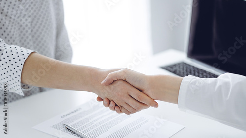 Business people shaking hands above contract papers just signed on the white table, closeup. Lawyers at meeting. Teamwork, partnership, success concept