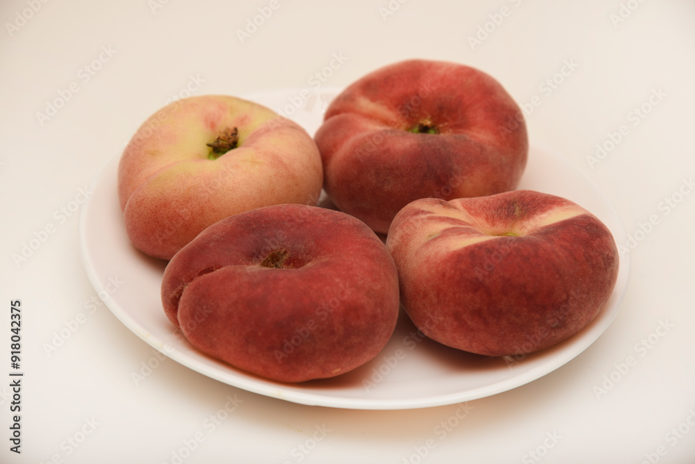 Flat peaches on a white plate. Delicious yellow peaches. Flat peaches on a white plate. Delicious yellow peaches.