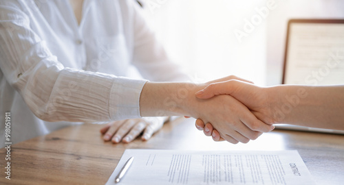 Business people shaking hands above contract papers just signed on the wooden table, close up. Lawyers at meeting. Teamwork, partnership, success concept