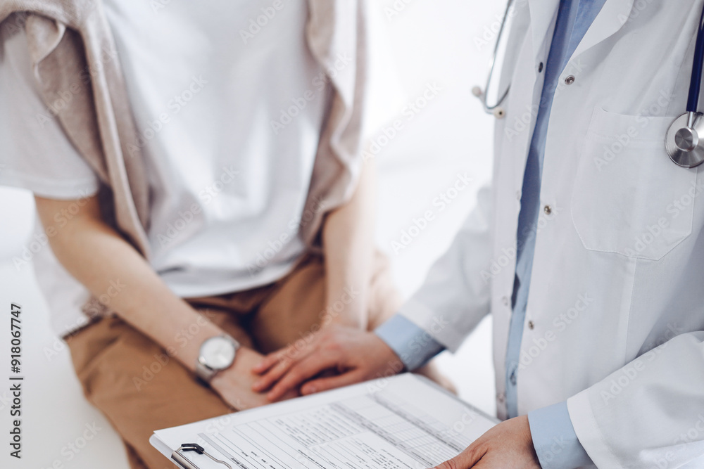 Doctor and patient in clinic. Friendly physician examining a young woman with a one hand while keeping a clipboard with medical records in another. Medicine concept