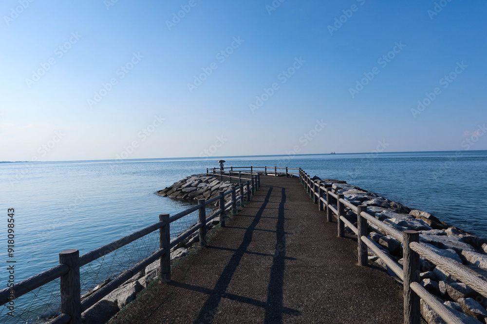 Wedded Rock, Ise, Mie, Japan- 19 Jul 2024: Serene Solitude, A Peaceful Pier Overlooking the Tranquil Waters. A bridge bath with wooden fence on both sides towards the sea. a lady standing at the end
Wedded Rock, Ise, Mie, Japan- 19 Jul 2024: Serene Solitude, A Peaceful Pier Overlooking the Tranquil Waters. A bridge bath with wooden fence on both sides towards the sea. a lady standing at the end