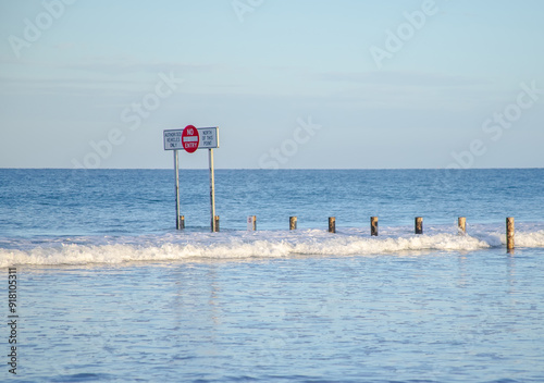 Photography No Entry road sign stands in water on beach, South Australia, paradoxical sign