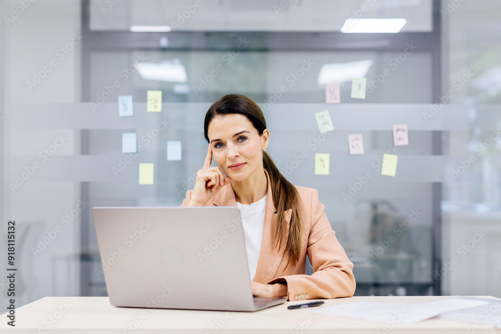 Stylish businesswoman, a director or marketing manager, works efficiently at her laptop in a modern coworking office. Ideal for themes of professionalism and workspace productivity. Stylish businesswoman, a director or marketing manager, works efficiently at her laptop in a modern coworking office. Ideal for themes of professionalism and workspace productivity.