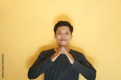 Young Asian man smiling when making triangle shape with his hand photo