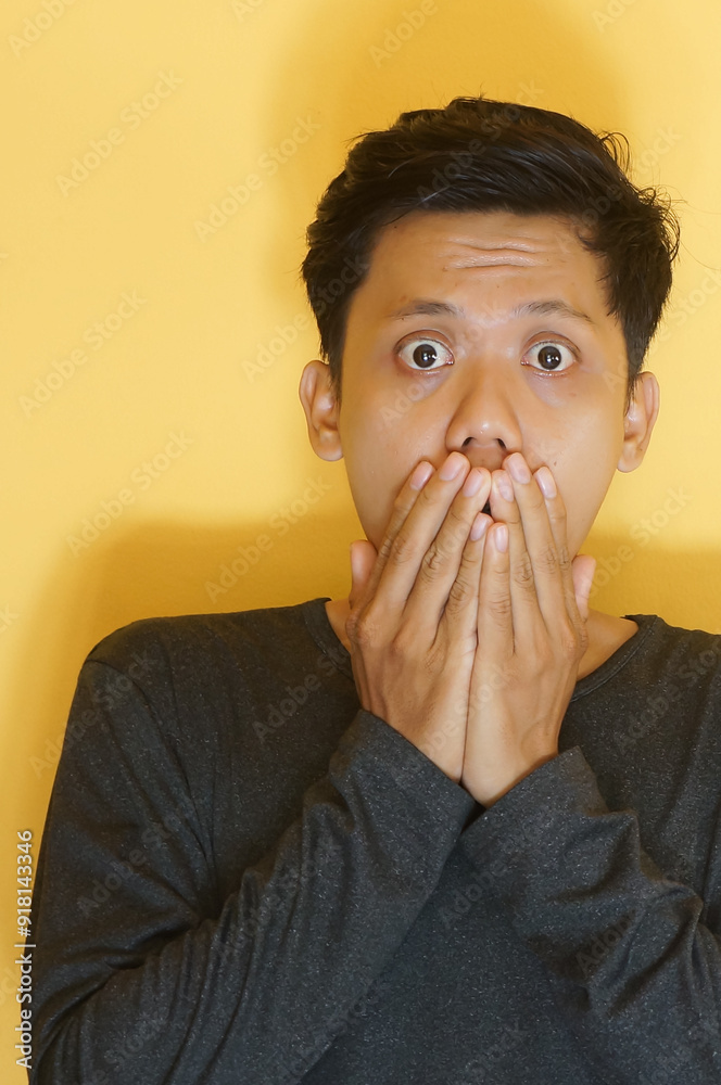 Shocked young Asian man with hand on his mouth Shocked young Asian man with hand on his mouth