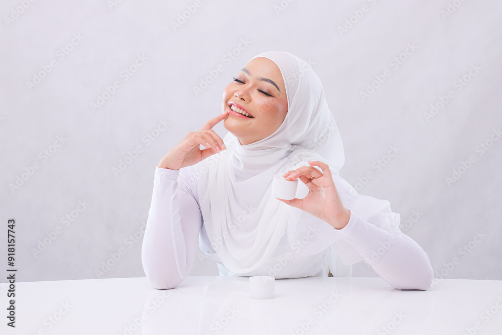 Gesture Beautiful young girl asia hijab laughing close eyes up hands hold lips and cosmetic cream in front of head to show skin care products on white background. health, medical and fashion concept Gesture Beautiful young girl asia hijab laughing close eyes up hands hold lips and cosmetic cream in front of head to show skin care products on white background. health, medical and fashion concept