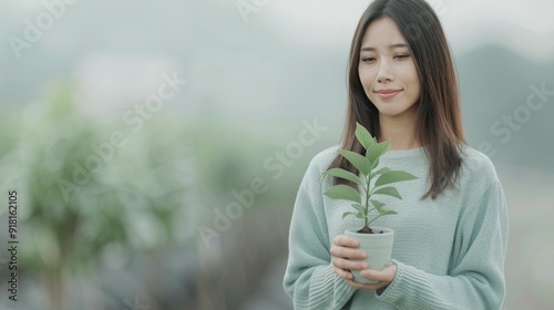 Woman Holding Small Potted Plant Indoors in Cozy Sweater During Daylight