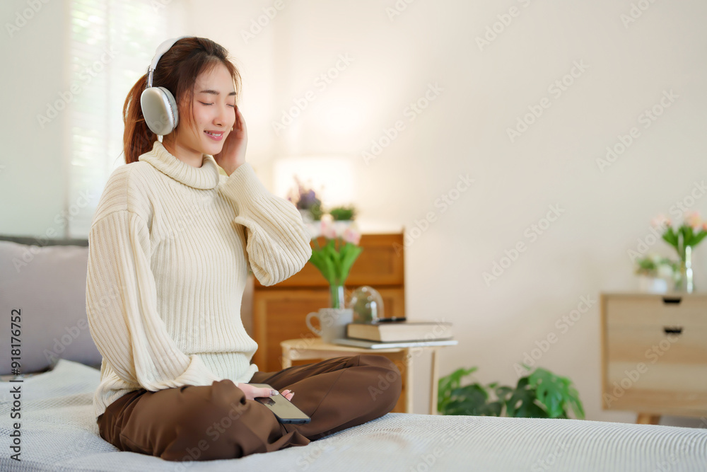 Young asian women in sweater wear headphone and close eyes to listening music with happiness while sitting on couch to relaxation and doing activity for spending time with slow life lifestyle at home Young asian women in sweater wear headphone and close eyes to listening music with happiness while sitting on couch to relaxation and doing activity for spending time with slow life lifestyle at home